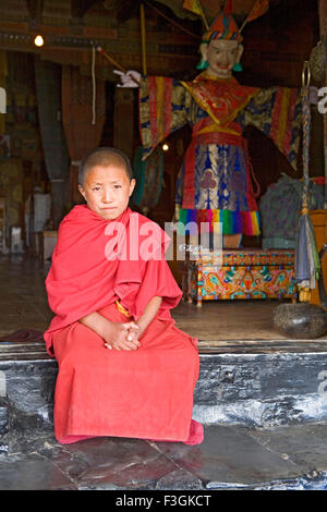 Un jeune lama dans sa robe rouge coin extérieur de la porte du temple de l'Tikse monastère bouddhiste ; Ladakh Jammu-et-Cachemire Banque D'Images