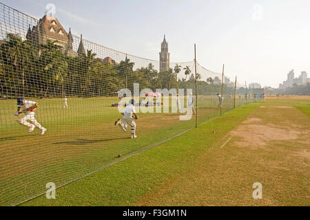 Les enfants jouer au cricket dans l'Oval maidan avec Tour Rajabai et la Haute Cour à l'arrière-plan ; Bombay Mumbai Maharashtra Banque D'Images