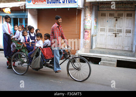 Des enfants à l'école en rickshaw vélo ; Haridwar ; Uttar Pradesh en Inde ; Banque D'Images