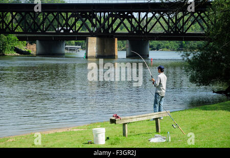 Pêche à partir de l'homme sur le pont de la rivière près du rivage. Banque D'Images