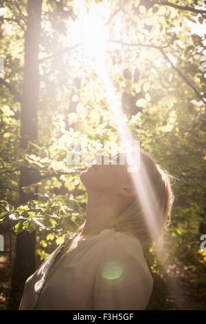 Mature Woman standing dans le flux de lumière en forêt Banque D'Images