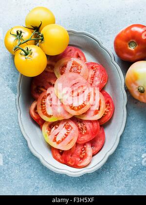Still Life of red des tranches de tomate dans le plat et des tomates jaunes Banque D'Images