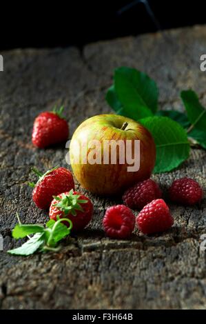 Framboises, fraises et Apple sur l'écorce des arbres Banque D'Images