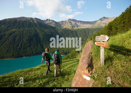 Vue arrière du jeune couple randonnée au réservoir Vernagt, Val Senales, Tyrol du Sud, Italie Banque D'Images