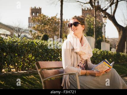 Young woman reading book sur banc, Parc de la Ciutadella, Barcelone, Espagne Banque D'Images