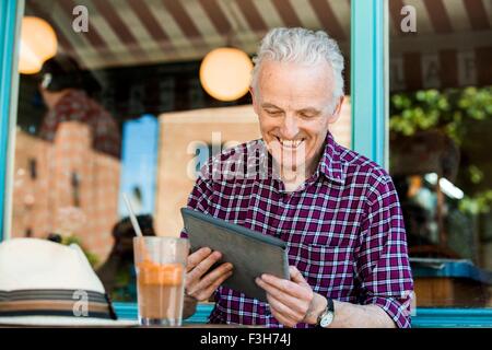 Senior man using digital tablet at cafe Banque D'Images