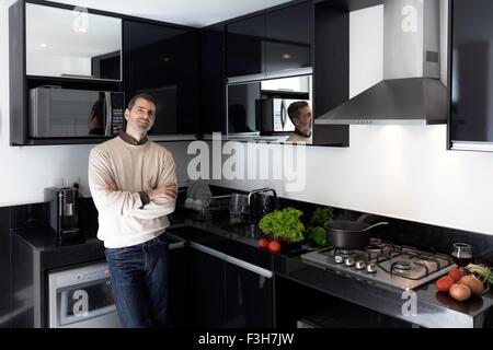 Couple dans la cuisine appuyé contre contre bras croisés, smiling Banque D'Images