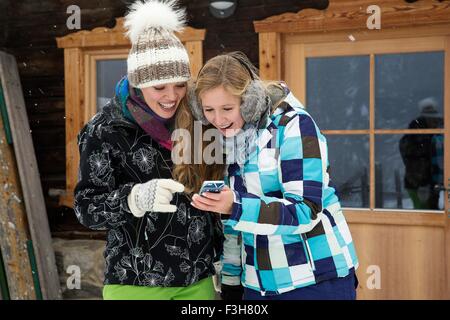 Les jeunes femmes avec le smartphone rire n'avant de hut Banque D'Images