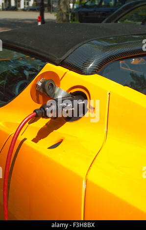 Orange lumineux voiture de sport électrique Tesla en cours de charge Banque D'Images