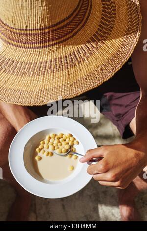 Portrait de jeune homme portant chapeau de manger des céréales pour petit déjeuner Banque D'Images