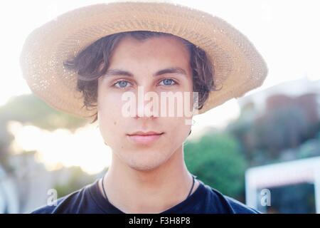 Close up portrait of young man wearing sunhat at beach