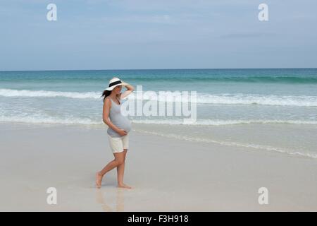 Pregnant woman wearing sunhat strolling on beach, Cap Vert, Afrique Banque D'Images