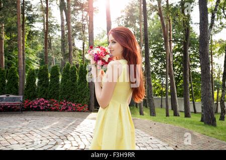 Young woman holding bunch of flowers in park Banque D'Images