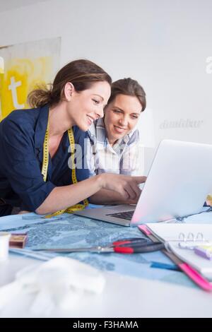 Les femmes mûres avec ruban de mesure en appui sur les coudes using laptop smiling Banque D'Images