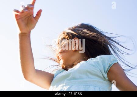 Low angle view of girl tourner autour de contre le ciel bleu Banque D'Images