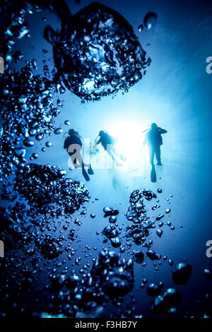 Silhouette de trois sous-marins plongeurs et bulles, Bali, Indonésie Banque D'Images
