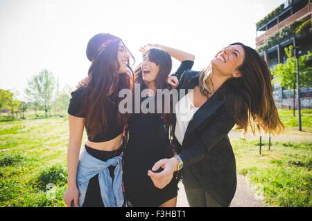 Trois jeunes femmes friends laughing together in park Banque D'Images