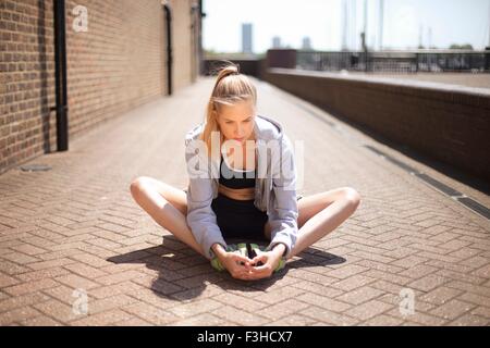 Runner stretching sur passerelle, Wapping, Londres Banque D'Images