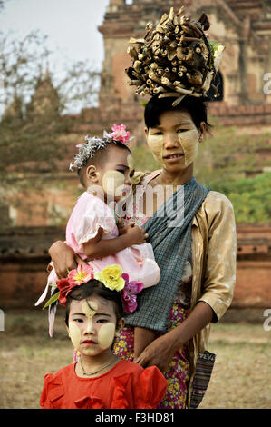 Jeune femme avec du bois sur sa tête et thanaka face paint avec ses filles à Bagan, Mandalay, Myanmar Région Banque D'Images