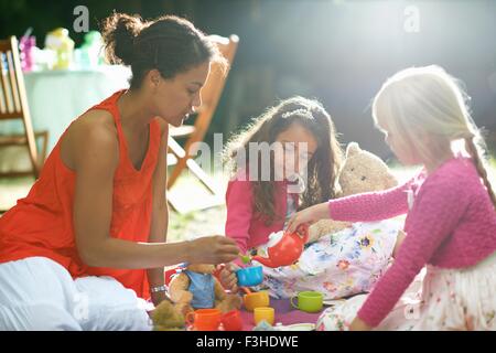 La mère et les deux filles de jouer au pique-nique d'anniversaire jardin Banque D'Images