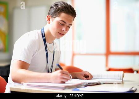 Male teenage student writing in file Banque D'Images