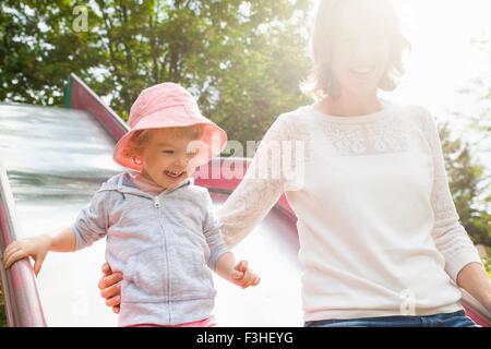 La mère et l'enfant de sexe féminin sur park slide Banque D'Images