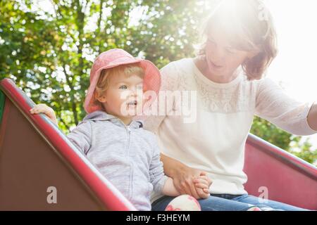 Mère et femme enfant jouant sur park slide Banque D'Images