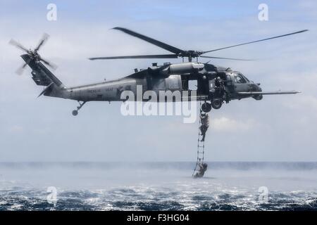 Les forces spéciales de l'US Air Force commandos sauvetage sauter du haut d'un HH-60G Pave Hawk dans l'océan lors d'entraînement amphibie appelé helo-casting le 7 octobre 2015 à Okinawa, au Japon. 320m d'aviateurs exécuter entraînement amphibie Banque D'Images