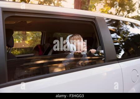 Boy wearing headphones contempler de la fenêtre de voiture Banque D'Images