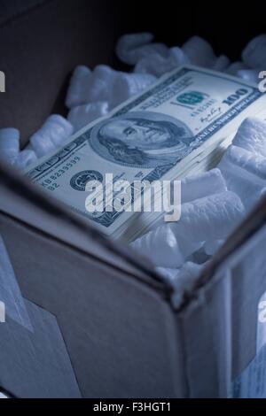 Pile de one hundred dollar bill in boîte en carton d'emballage en mousse avec des arachides Banque D'Images