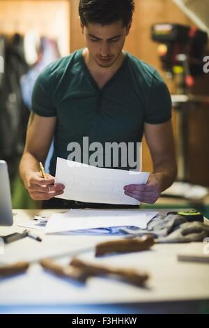 Young man holding paper travail, regardant vers le bas Banque D'Images