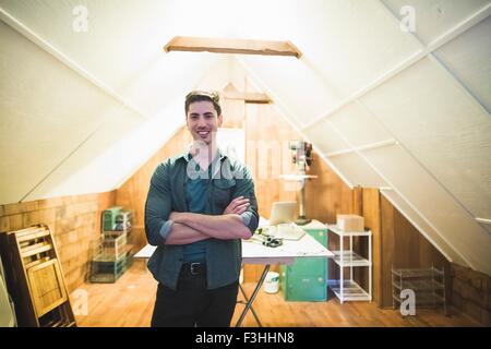 Jeune homme debout dans l'espace, les bras croisés, smiling at camera Banque D'Images