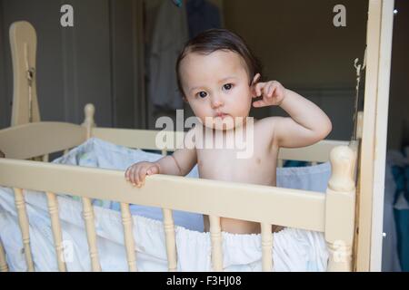 Portrait de las baby boy standing in crib Banque D'Images