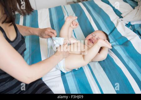 Mature mother changer bébé fils nappy on bed Banque D'Images