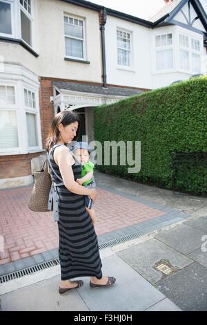 Mature mother and son dans la rue se promener le long de l'écharpe porte-bébé Banque D'Images
