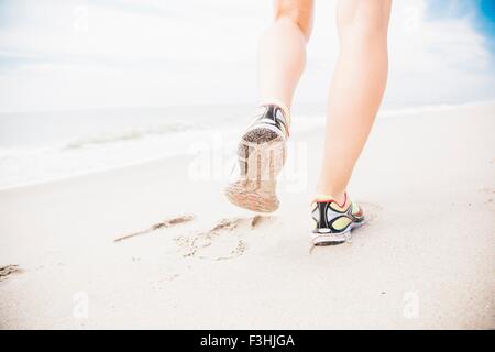 Mid adult woman walking on beach, vue arrière, low section Banque D'Images