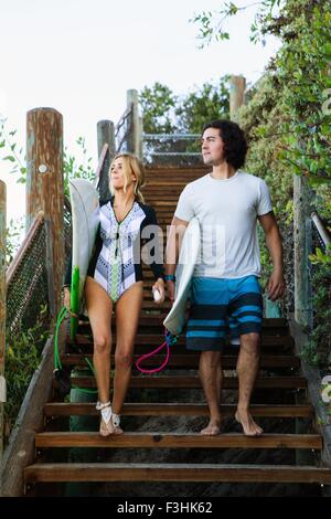 Couple walking down steps, transportant des planches Banque D'Images