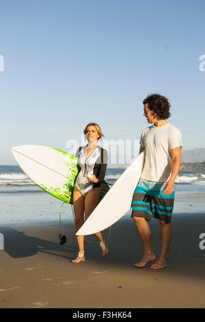 Couple walking on beach, transportant des planches Banque D'Images