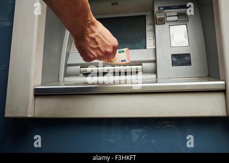 Mid adult man using cash machine, se concentrer sur les mains Banque D'Images