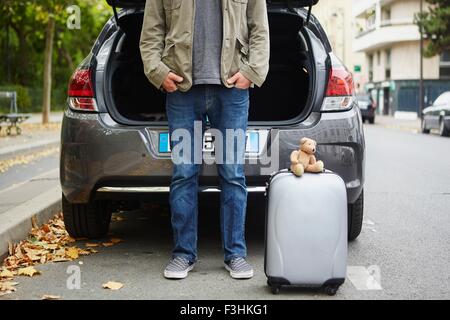 Mid adult man standing à côté de voiture avec valise, open boot dans road Banque D'Images