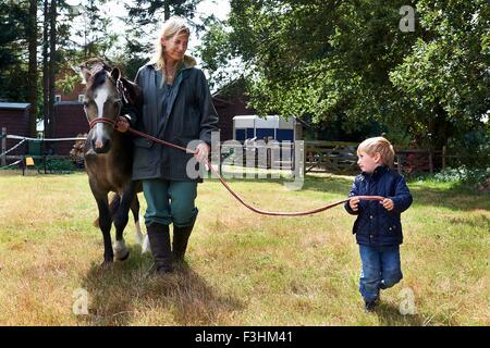 Petit garçon et sa mère menant au champ de poney Banque D'Images