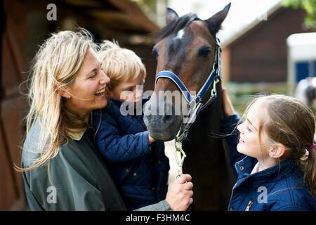 Femme mature avec son fils et sa fille petting horse Banque D'Images