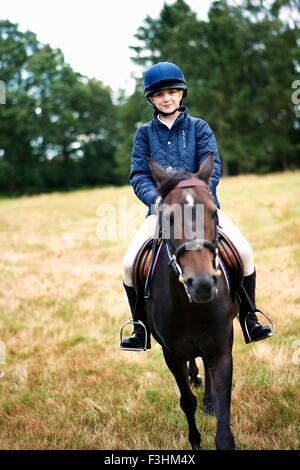 Portrait de jeune fille l'équitation dans le champ Banque D'Images