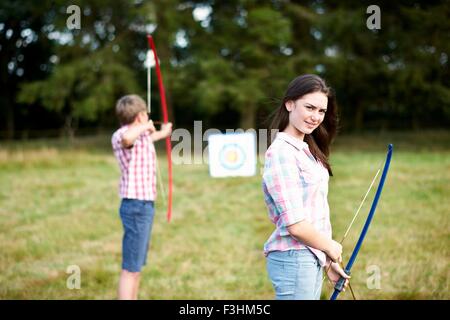 Portrait of teenage girl practicing archery avec frère Banque D'Images