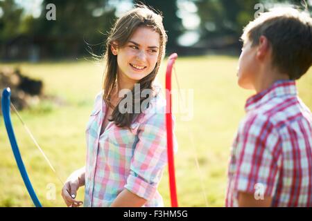 Teenage girl talking à son frère tout en pratiquant le tir à l'ARC Banque D'Images