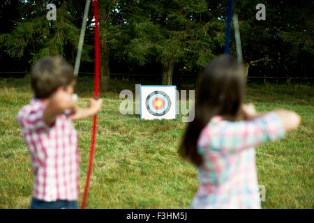 Vue arrière du frère et sœur adolescente practicing archery Banque D'Images