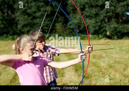 Fille et frère d'adolescent practicing archery Banque D'Images