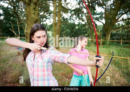 Fille et sœur adolescente practicing archery Banque D'Images