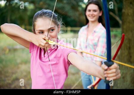 Girl practicing archery visant avec arc et flèche Banque D'Images