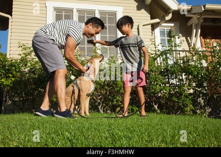 Père et fils petting dog in garden Banque D'Images